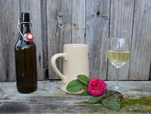 Bierflasche und Glas, daneben ein volles Glas Wein und eine Blume auf dem Tisch