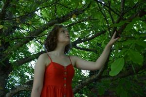 Frau im roten Kleid am Baum stehend