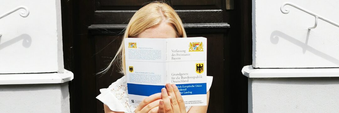 Frau mit Dem Grundgesetzbuch vor dem Gesicht