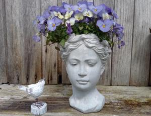 Frauenkopf als Vase mit Blumen, daneben eine kleine Vogelstatue