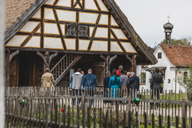 Menschen stehen bei einer Führung vor einem historischen Fachwerkhaus.