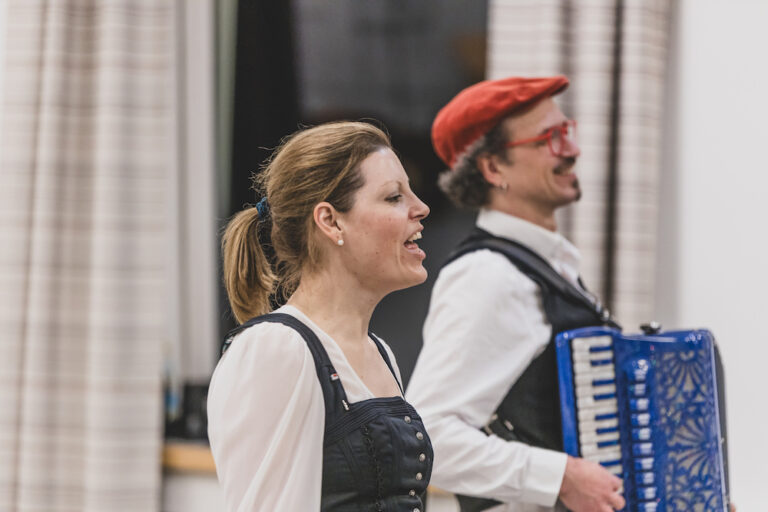 Carolin Pruy-Popp und David Saam in Tracht, seitlich. Carolin Pruy-Popp singend, David Saam mit Akkordeon.