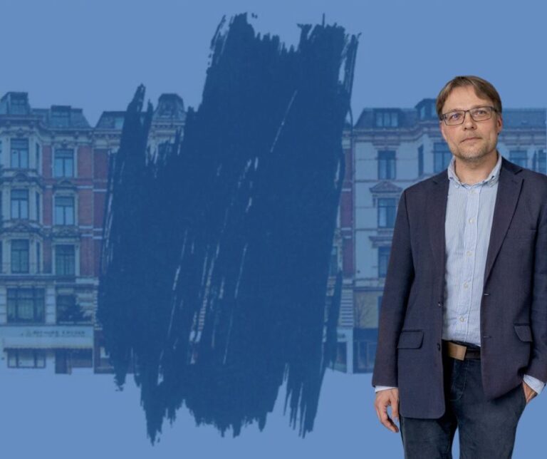 Dr. Martin Bredenbeck vor einem Ausschnitt eines Plakats. Ein Haus einer Häuserzeile aus dem 19. Jahrhundert ist wegradiert.