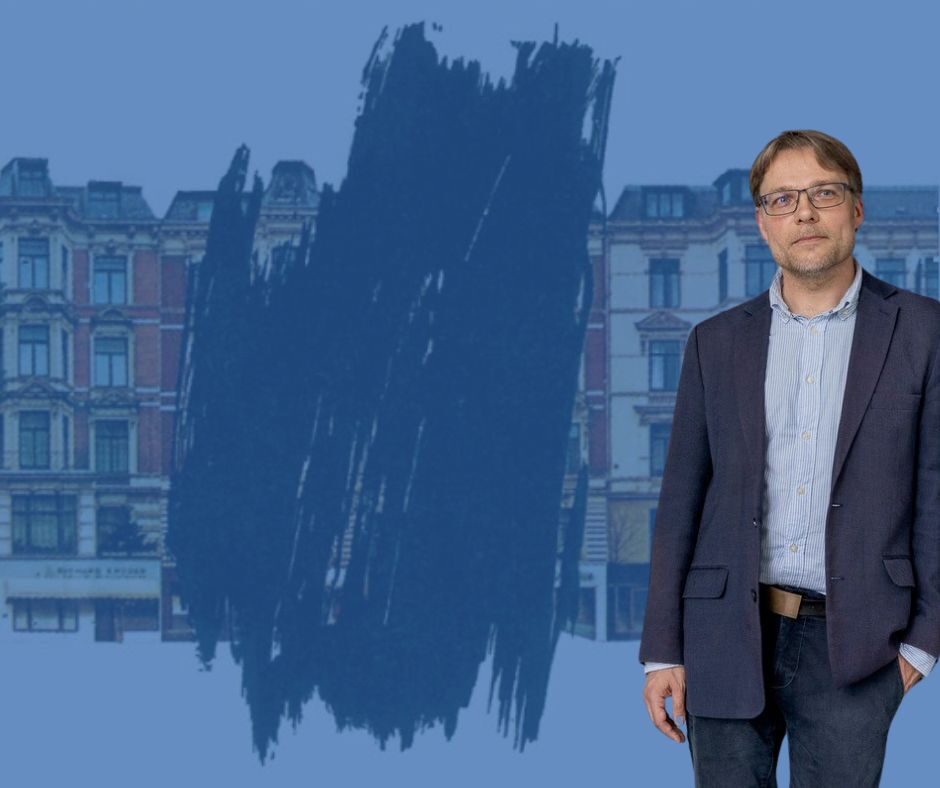 Dr. Martin Bredenbeck vor einem Ausschnitt eines Plakats. Ein Haus einer Häuserzeile aus dem 19. Jahrhundert ist wegradiert.