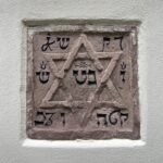 Stein mit hebräischen Schriftzeichen und Davidstern in einer Hausfassade