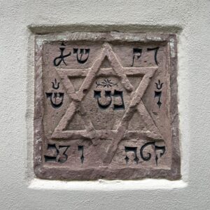 Stein mit hebräischen Schriftzeichen und Davidstern in einer Hausfassade