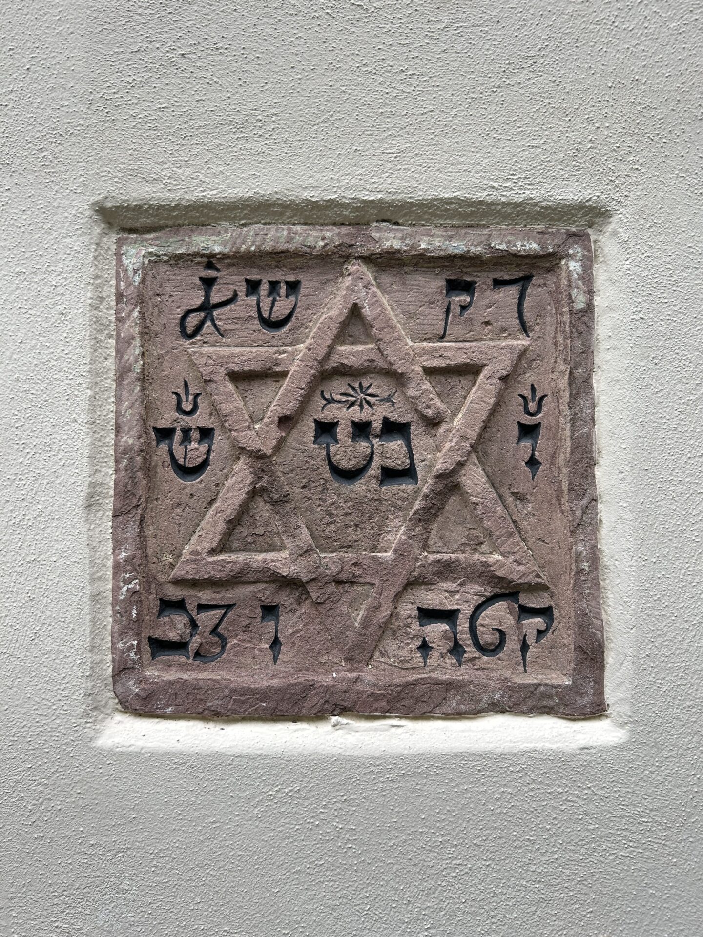 Stein mit hebräischen Schriftzeichen und Davidstern in einer Hausfassade
